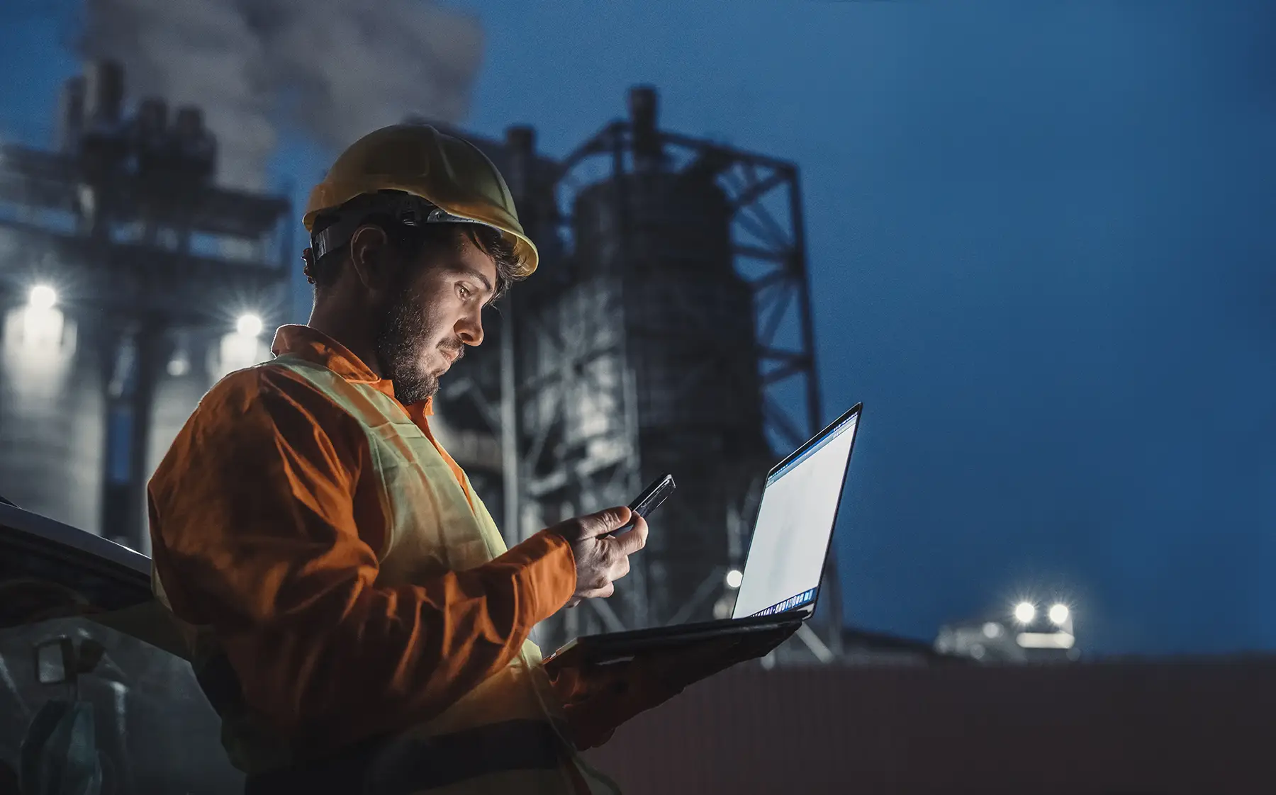 Oil and gas worker looking at computer and phone screen